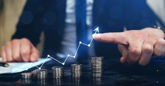 Hand pointing to a rising cash-flow chart above stacked coins