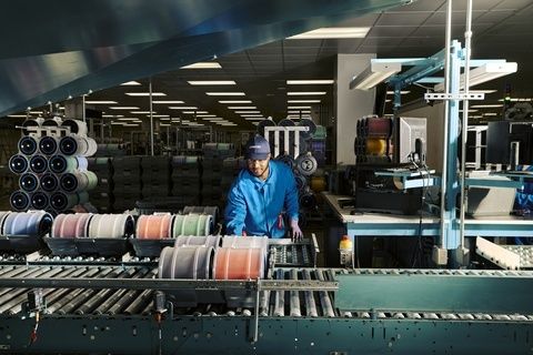 Worker overseeing a textile production line in a manufacturing facility