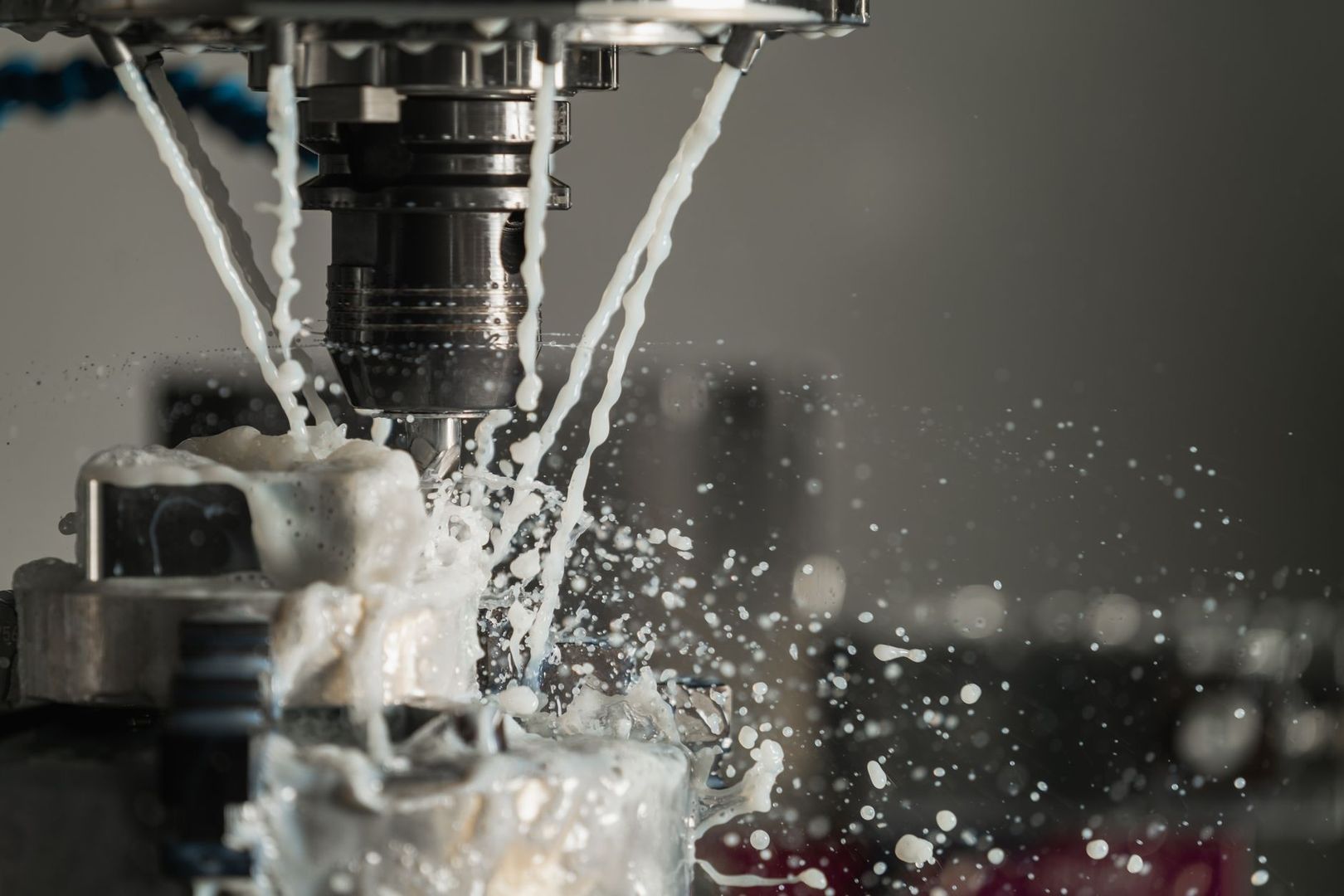 CNC cutting tool machining a metal part amid splashing coolant
